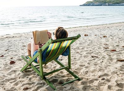 Image of a woman reading a book on a beach